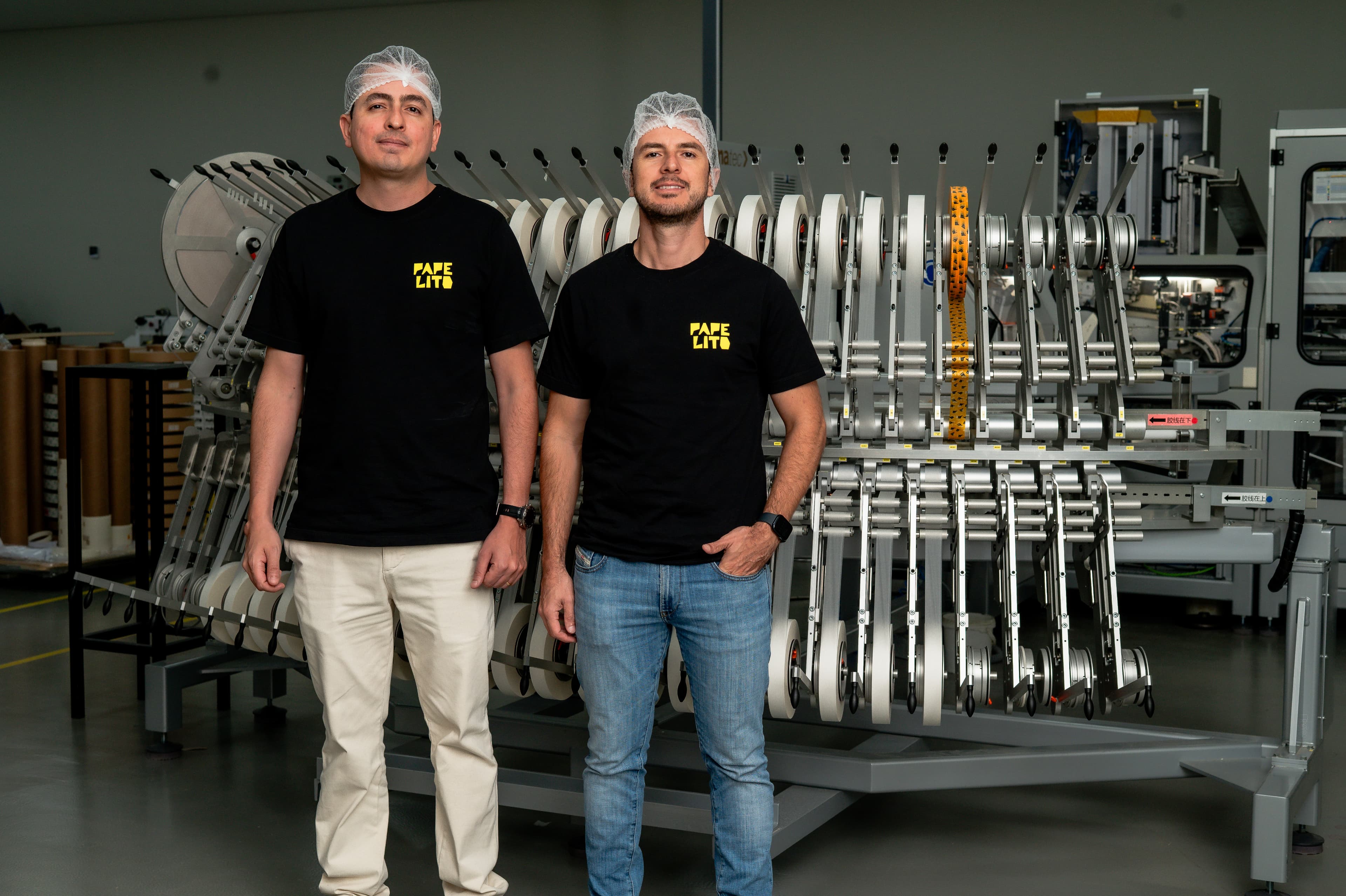 Sócios da Papelito em pé diante da linha de produção da fábrica.
